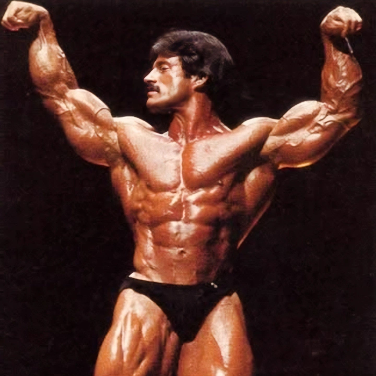 Muscular man flexing his arms against a dark background